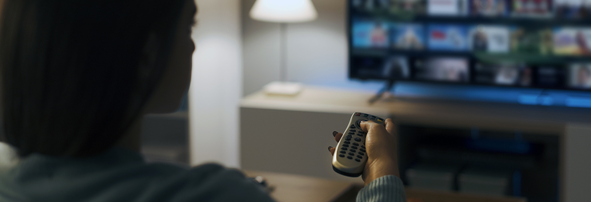 woman sitting on the couch pointing a remote to a television