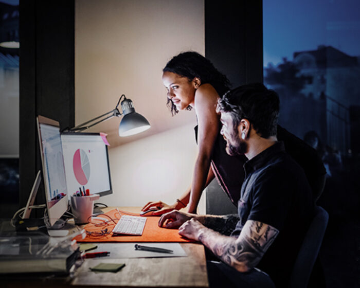 two people working run an office looking at a computer screen