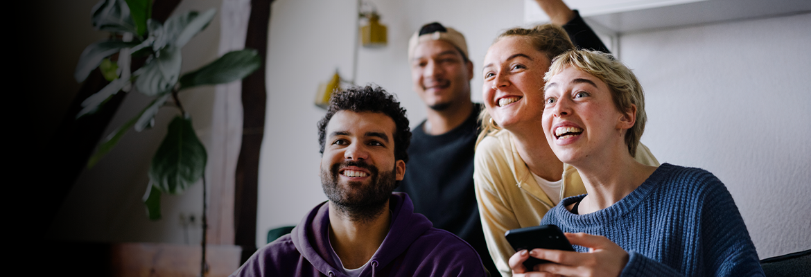 Diverse group of friends smiling laughing and watching TV