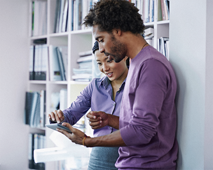 two people in a business setting looking at a tablet