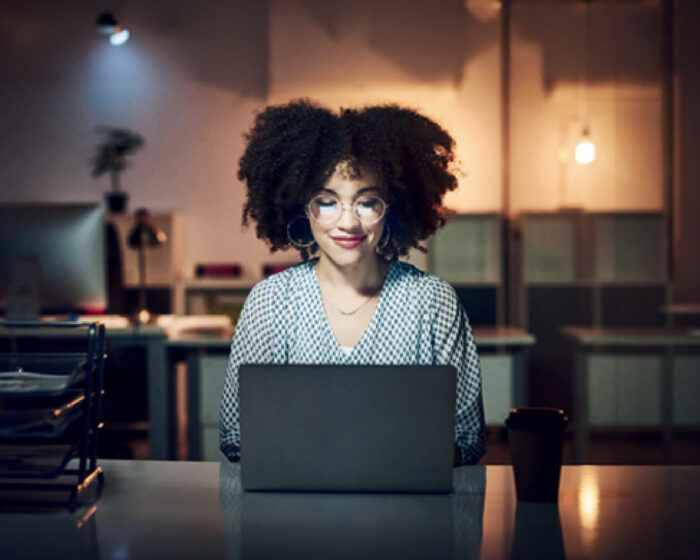 Woman working on a laptop at a desk in a softly lit office