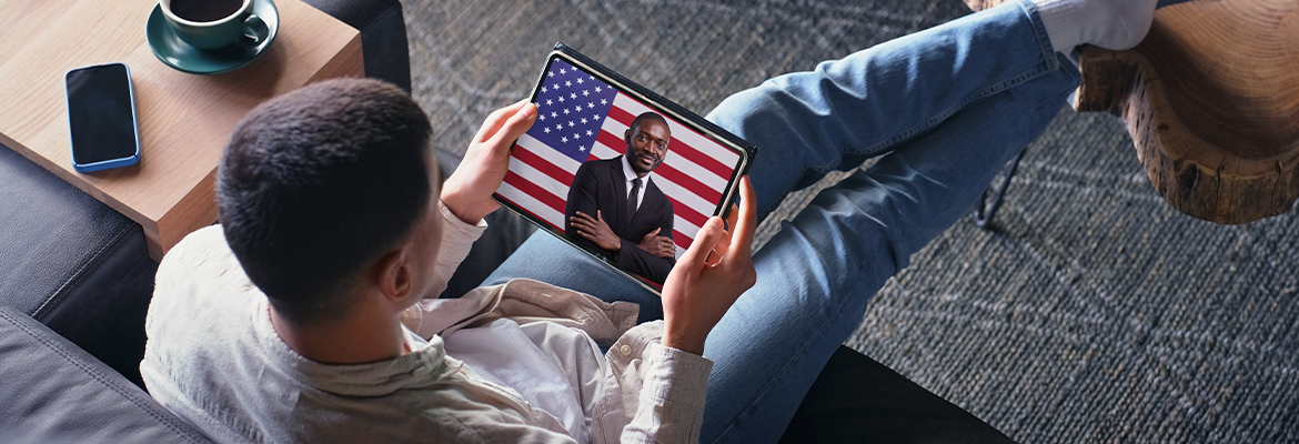 Man on couch watching American political ad on tablet screen