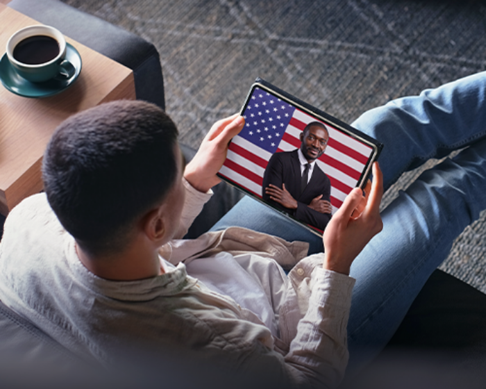 Man on couch watching American political ad on tablet screen